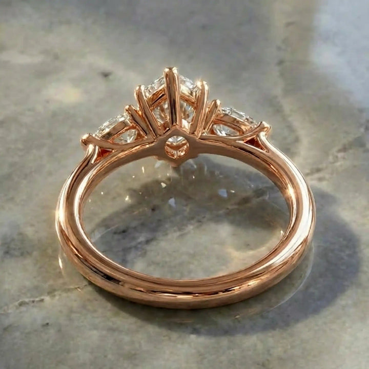 Marquise lab-grown diamond three-stone engagement ring with pear side stones on a polished surface.
