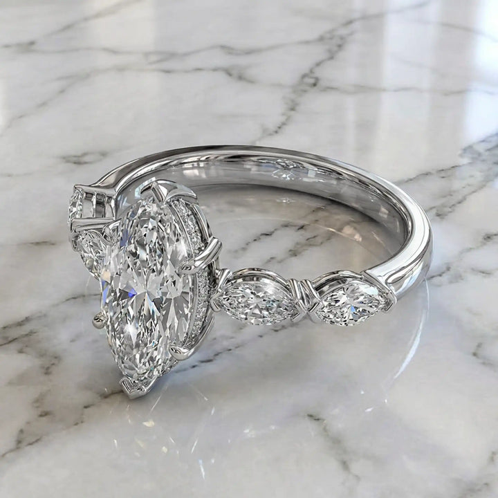 2 carat marquise lab diamond engagement ring with hidden halo and marquise accent band on marbel.
