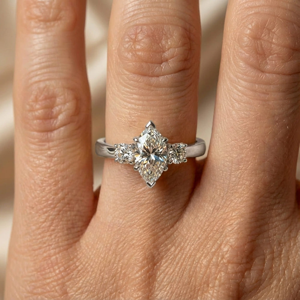 Marquise three-stone lab-grown diamond engagement ring displayed on soft fabric.