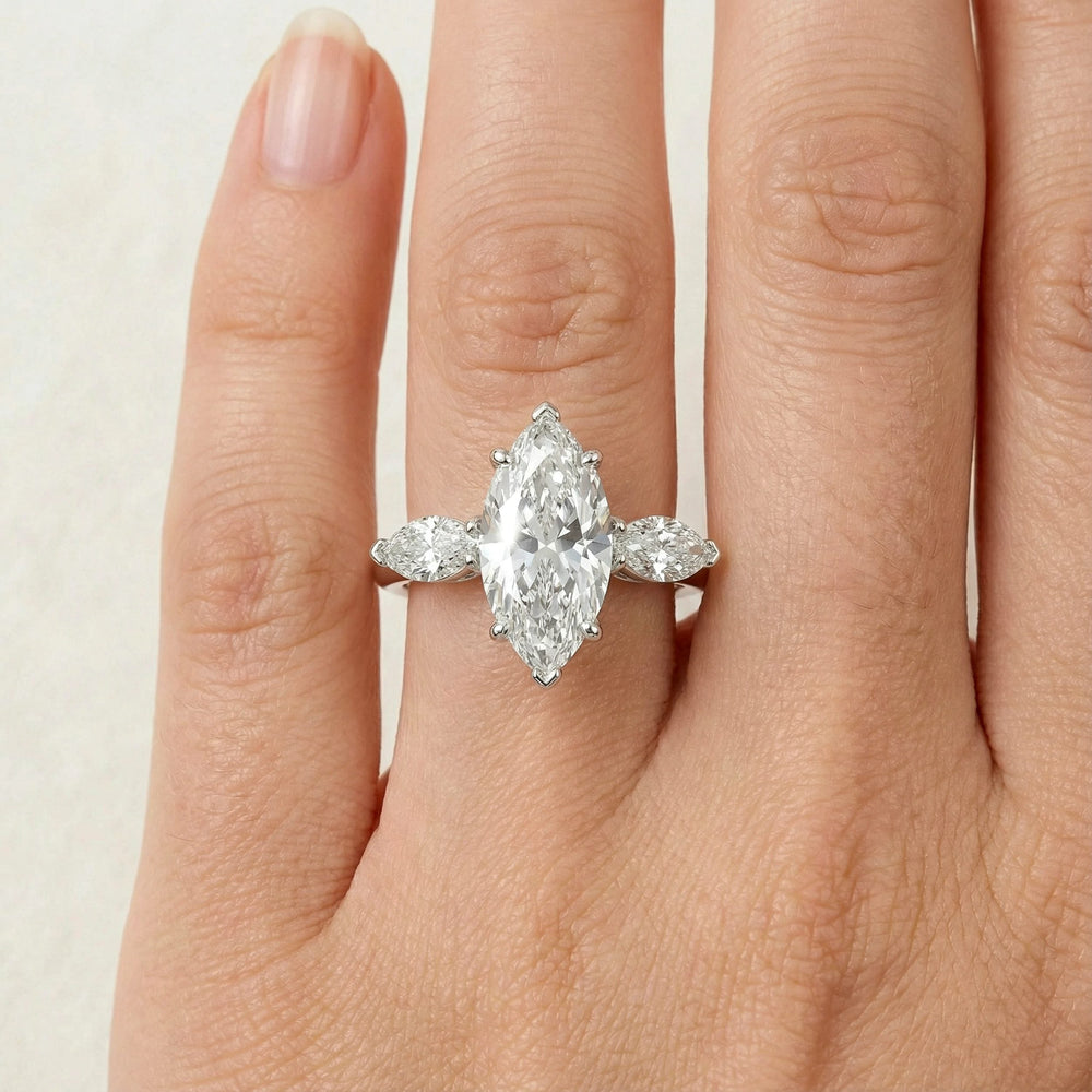 Marquise three-stone lab-grown diamond engagement ring shown on reflective surface.