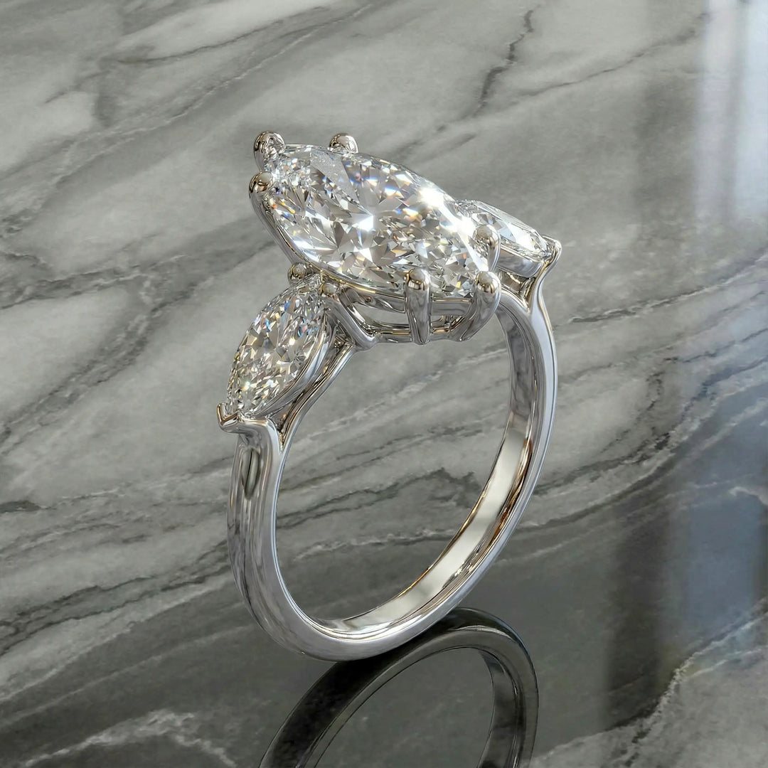 Marquise three-stone lab-grown diamond engagement ring shown on reflective surface.
