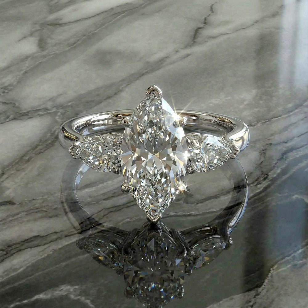 Marquise three-stone lab-grown diamond engagement ring shown on reflective surface.
