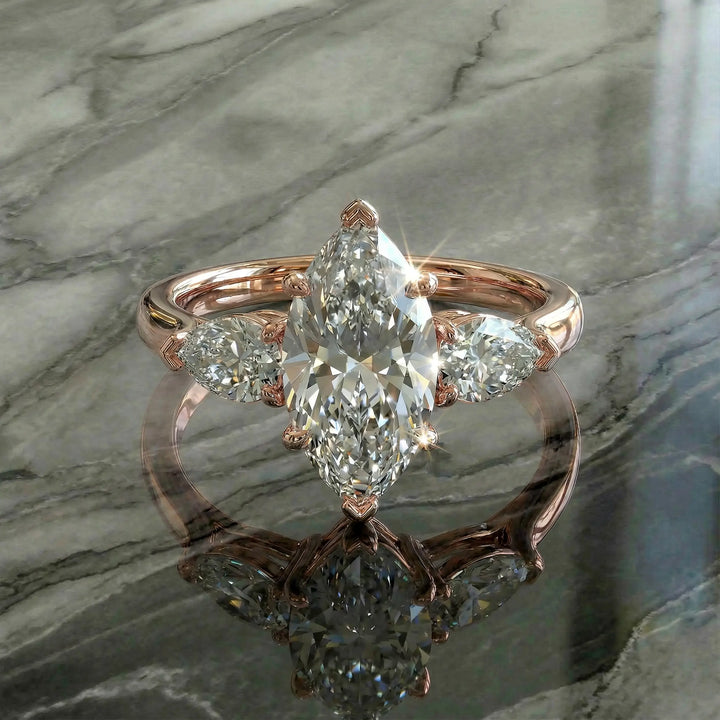 Marquise three-stone lab-grown diamond engagement ring shown on reflective surface.
