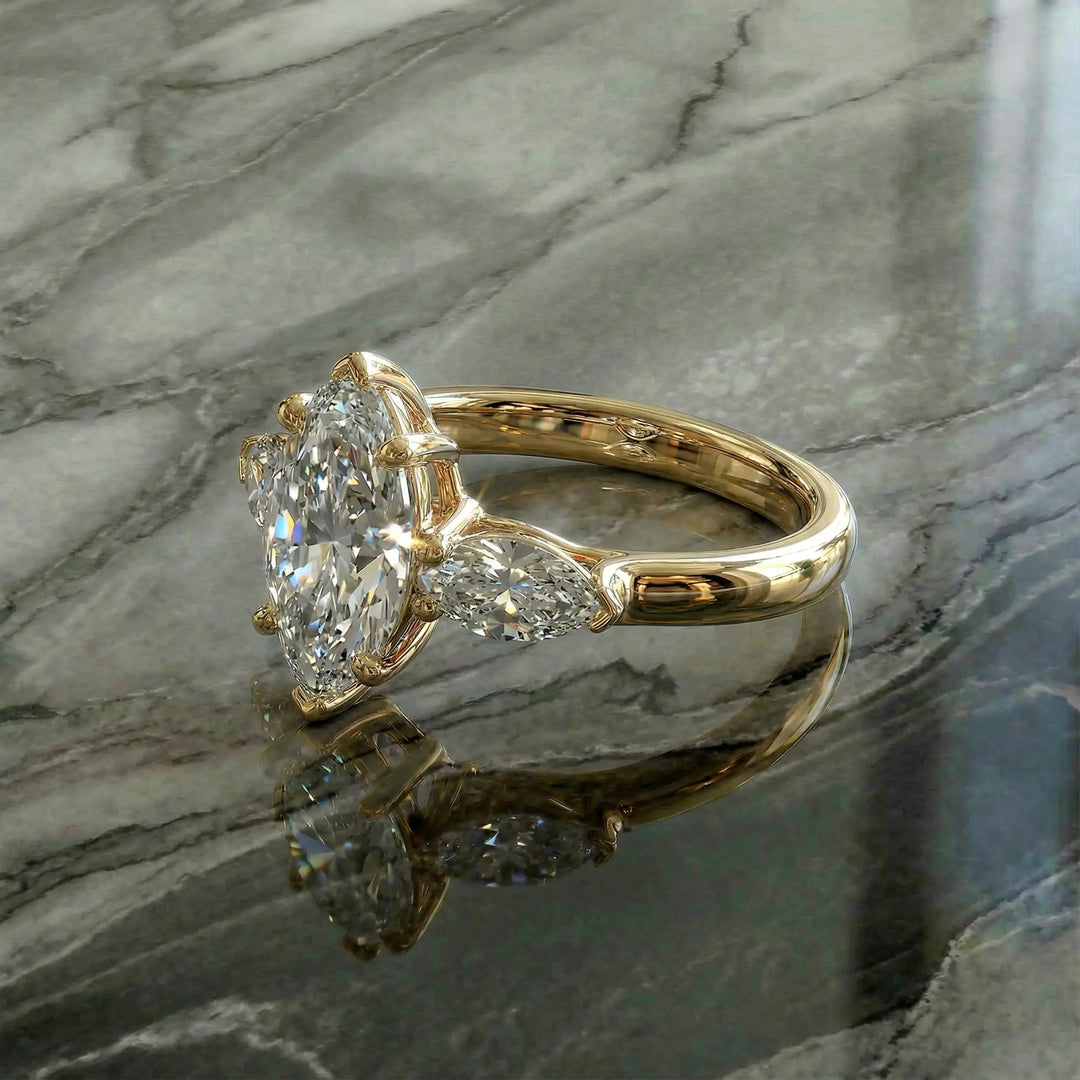 Marquise three-stone lab-grown diamond engagement ring shown on reflective surface.
