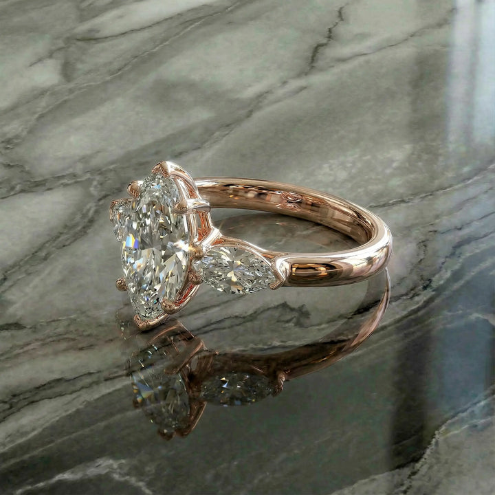 Marquise three-stone lab-grown diamond engagement ring shown on reflective surface.
