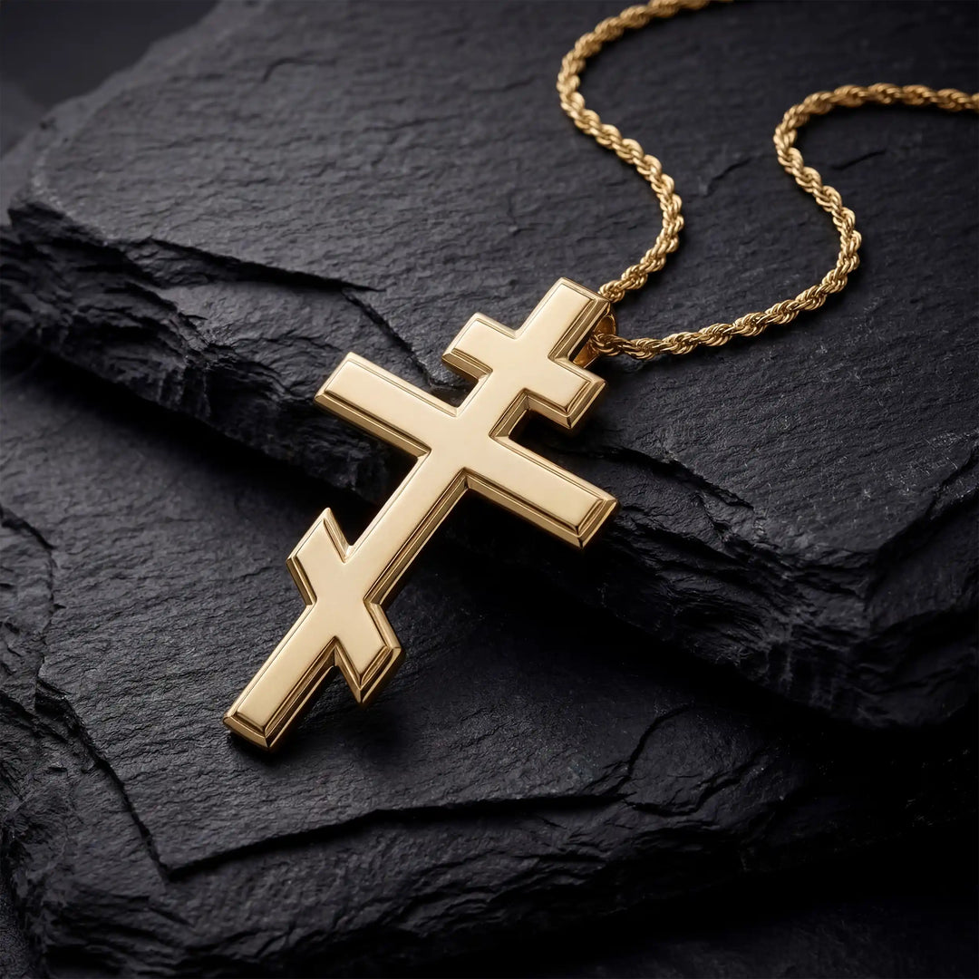 Orthodox three-bar Christian cross pendant displayed on black stone.