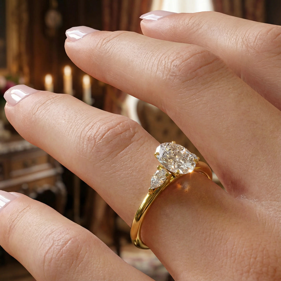 Oval diamond engagement ring with pear-shaped side stones front view.