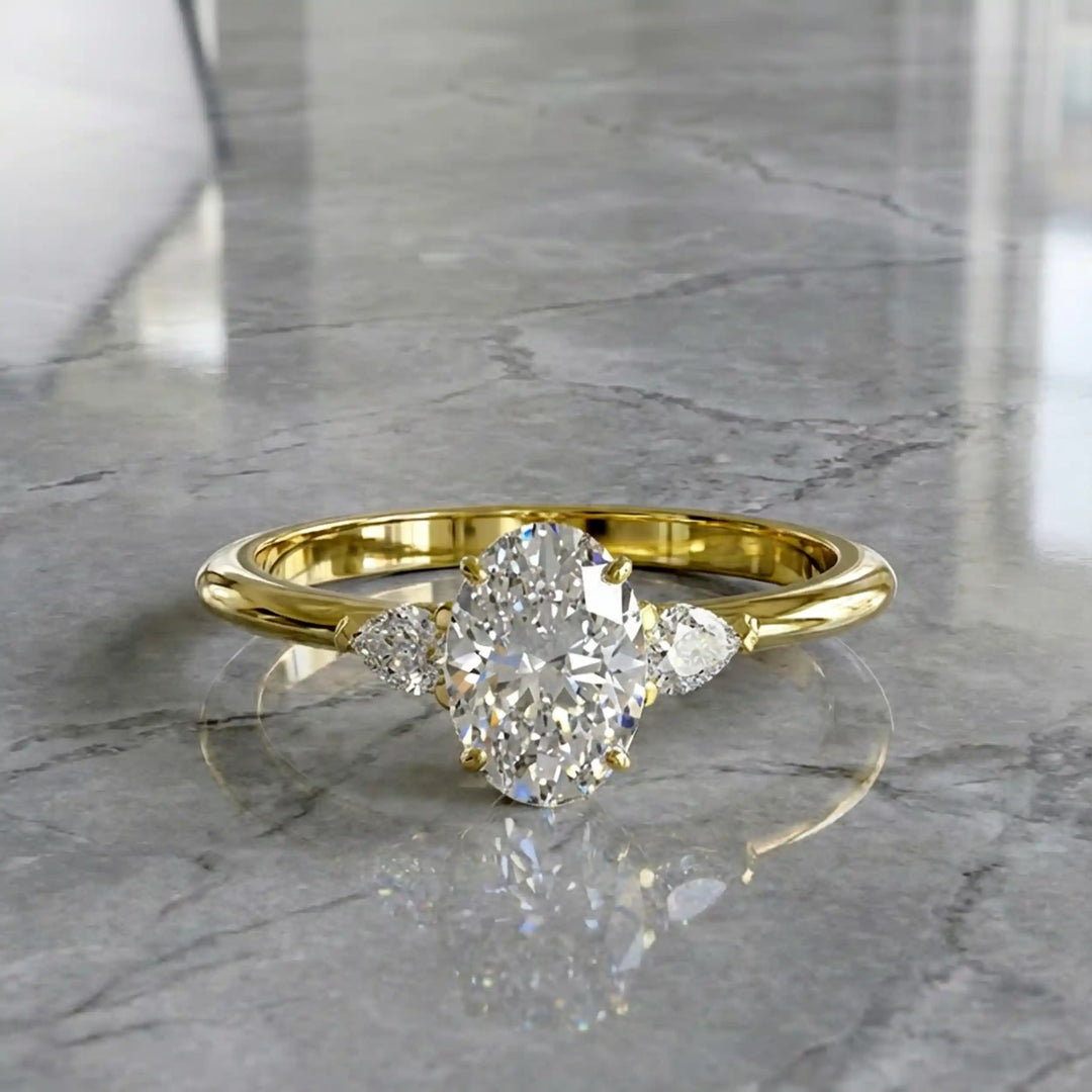Oval diamond engagement ring with pear-shaped side stones front view.