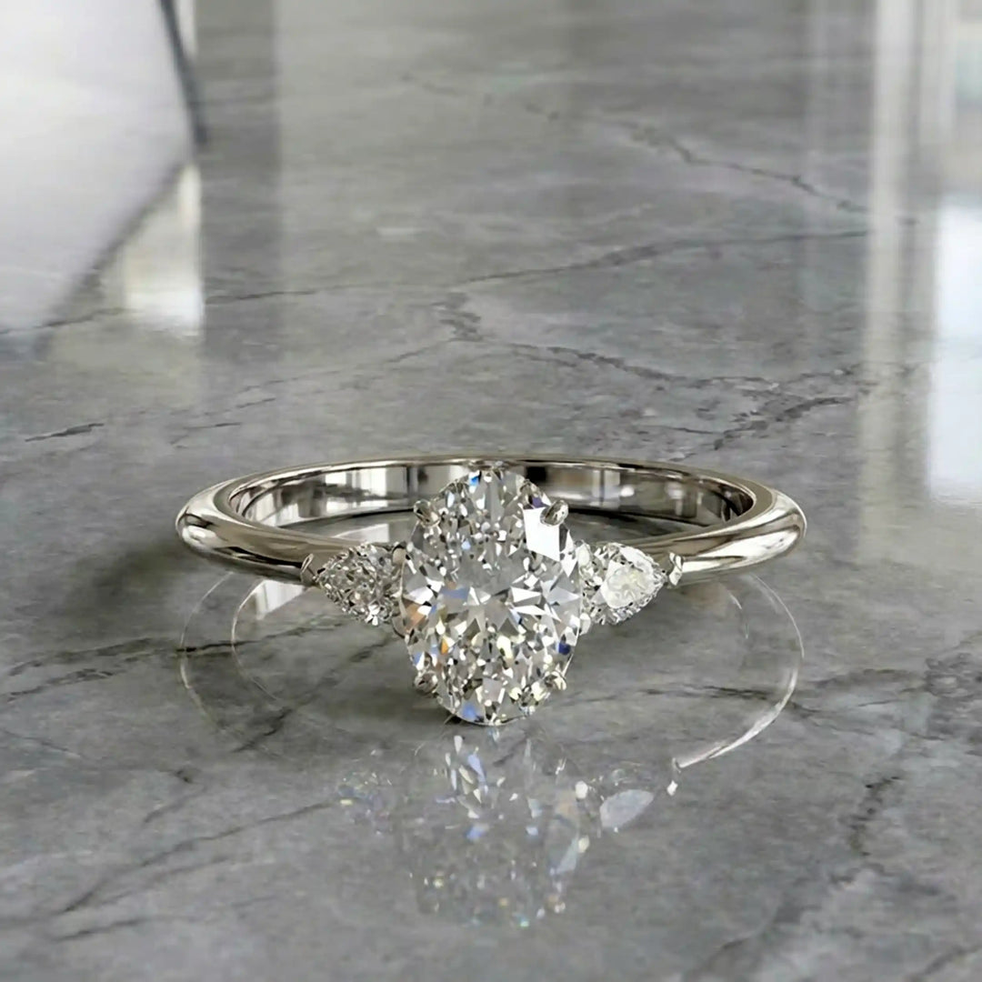 Oval diamond engagement ring with pear-shaped side stones front view.