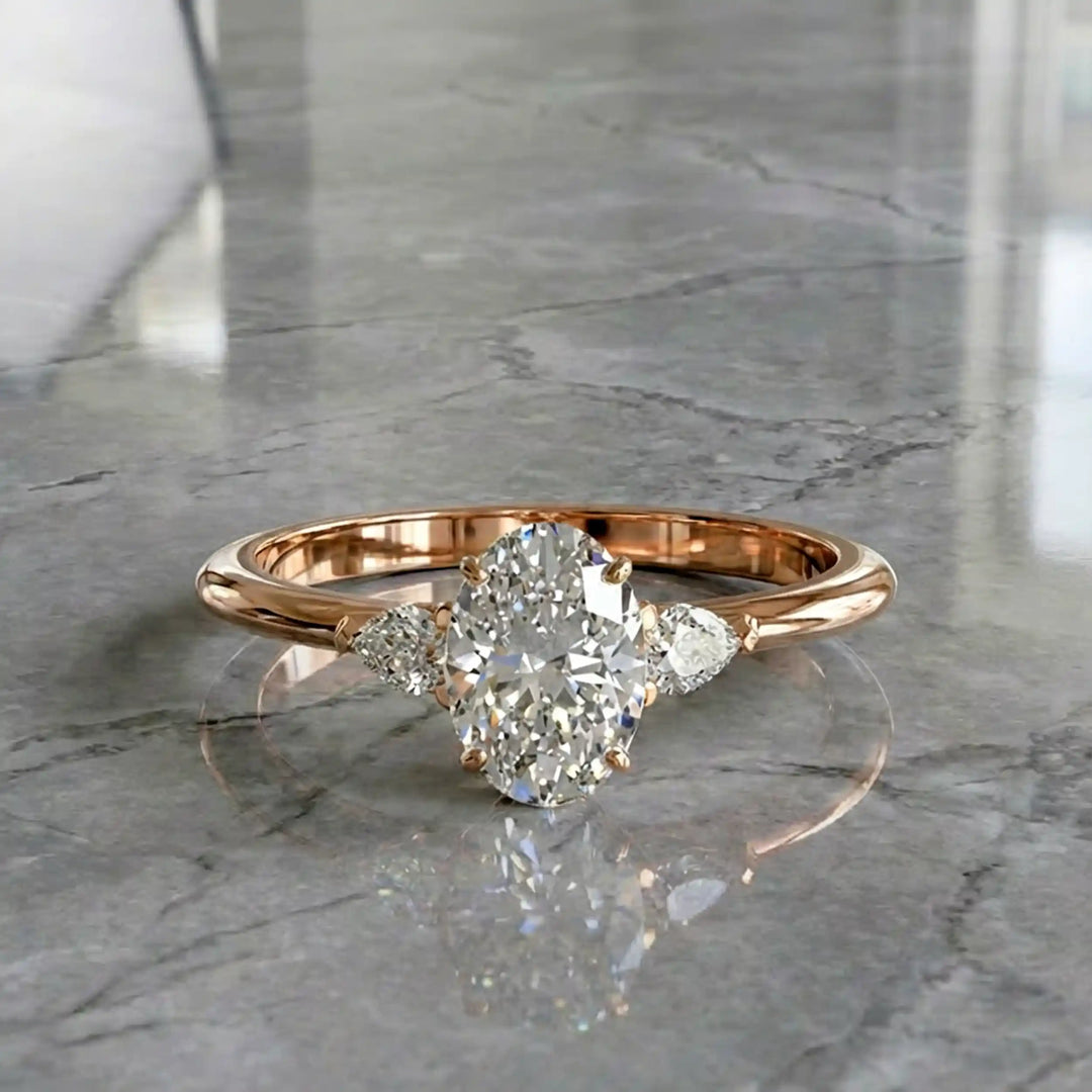 Oval diamond engagement ring with pear-shaped side stones front view.