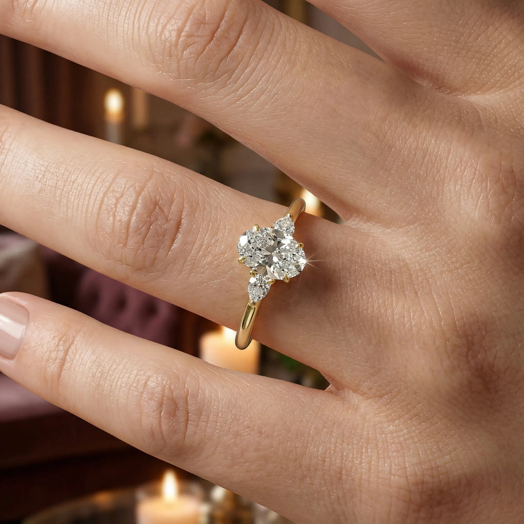 Oval diamond engagement ring with pear-shaped side stones front view.