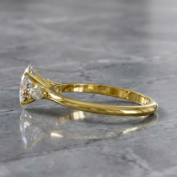 Oval diamond engagement ring with pear-shaped side stones front view.
