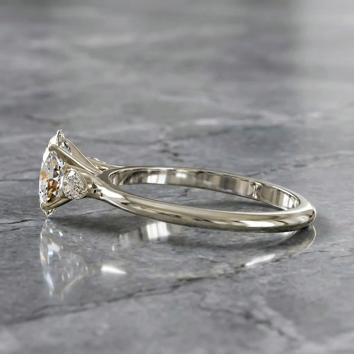 Oval diamond engagement ring with pear-shaped side stones front view.
