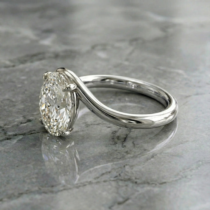 Oval lab-grown diamond solitaire engagement ring shown in cathedral setting on reflective surface.
