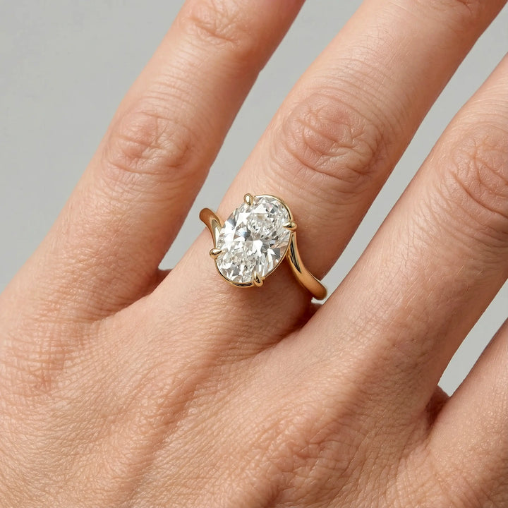 Oval lab-grown diamond solitaire engagement ring shown in cathedral setting on hand.
