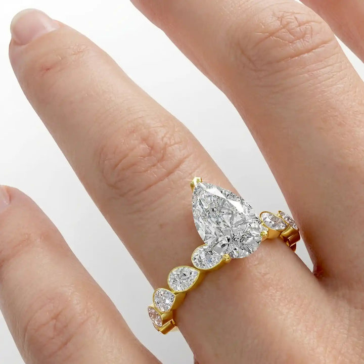 Pear lab-grown diamond engagement ring with bezel-set pear side stones displayed on hand.