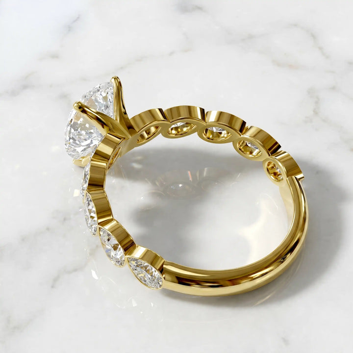 Pear lab-grown diamond engagement ring with bezel-set pear side stones displayed on surface.