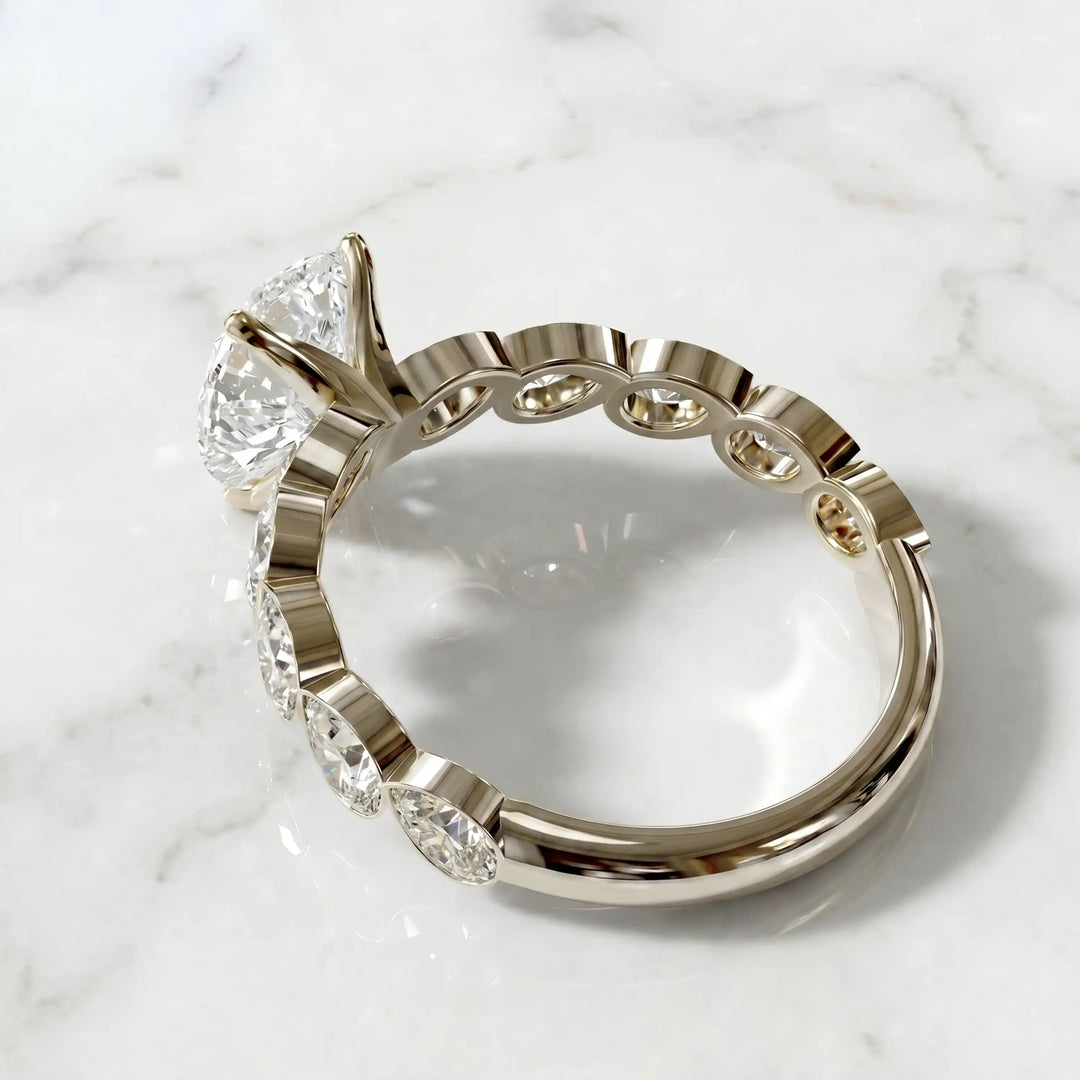 Pear lab-grown diamond engagement ring with bezel-set pear side stones displayed on surface.