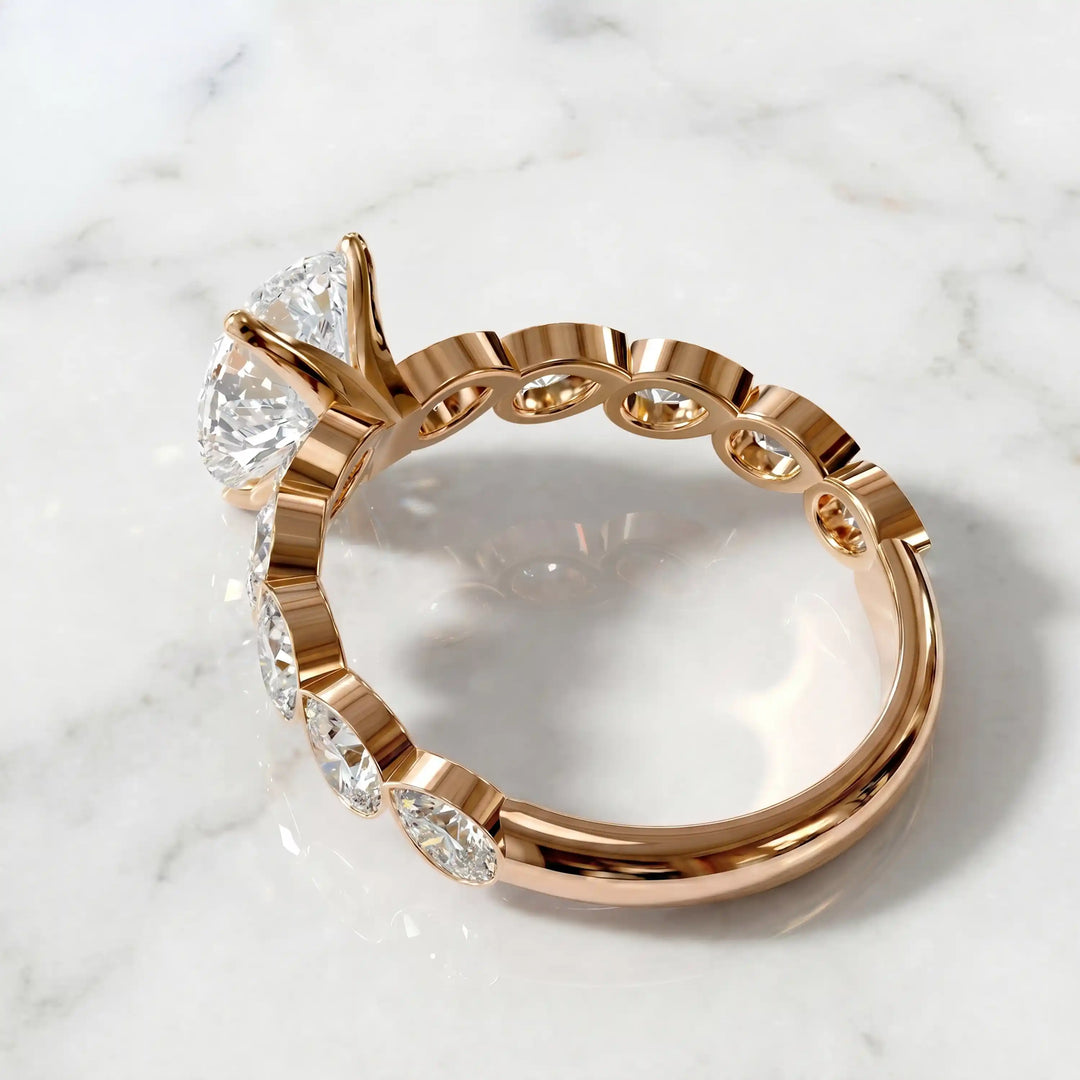 Pear lab-grown diamond engagement ring with bezel-set pear side stones displayed on surface.