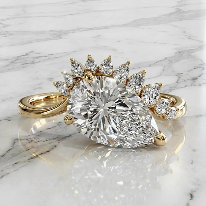 2.5 carat pear lab-grown diamond engagement ring with pear accents displayed on marble surface.
