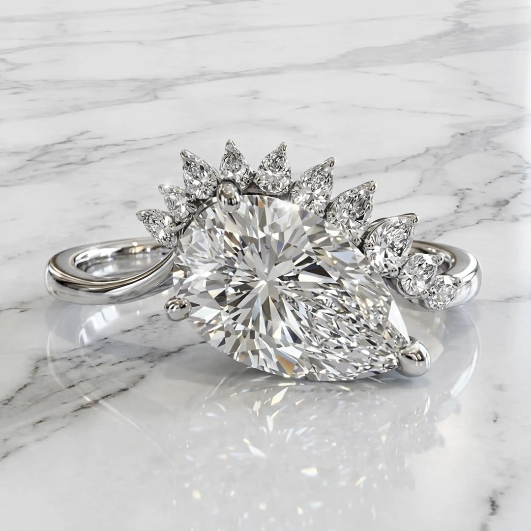 2.5 carat pear lab-grown diamond engagement ring with pear accents displayed on marble surface.
