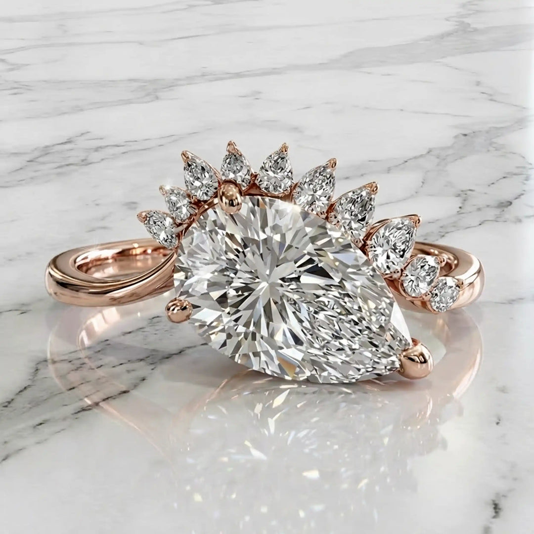 2.5 carat pear lab-grown diamond engagement ring with pear accents displayed on marble surface.
