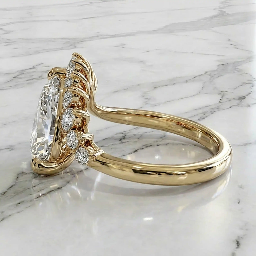 2.5 carat pear lab-grown diamond engagement ring with pear accents displayed on marble surface.
