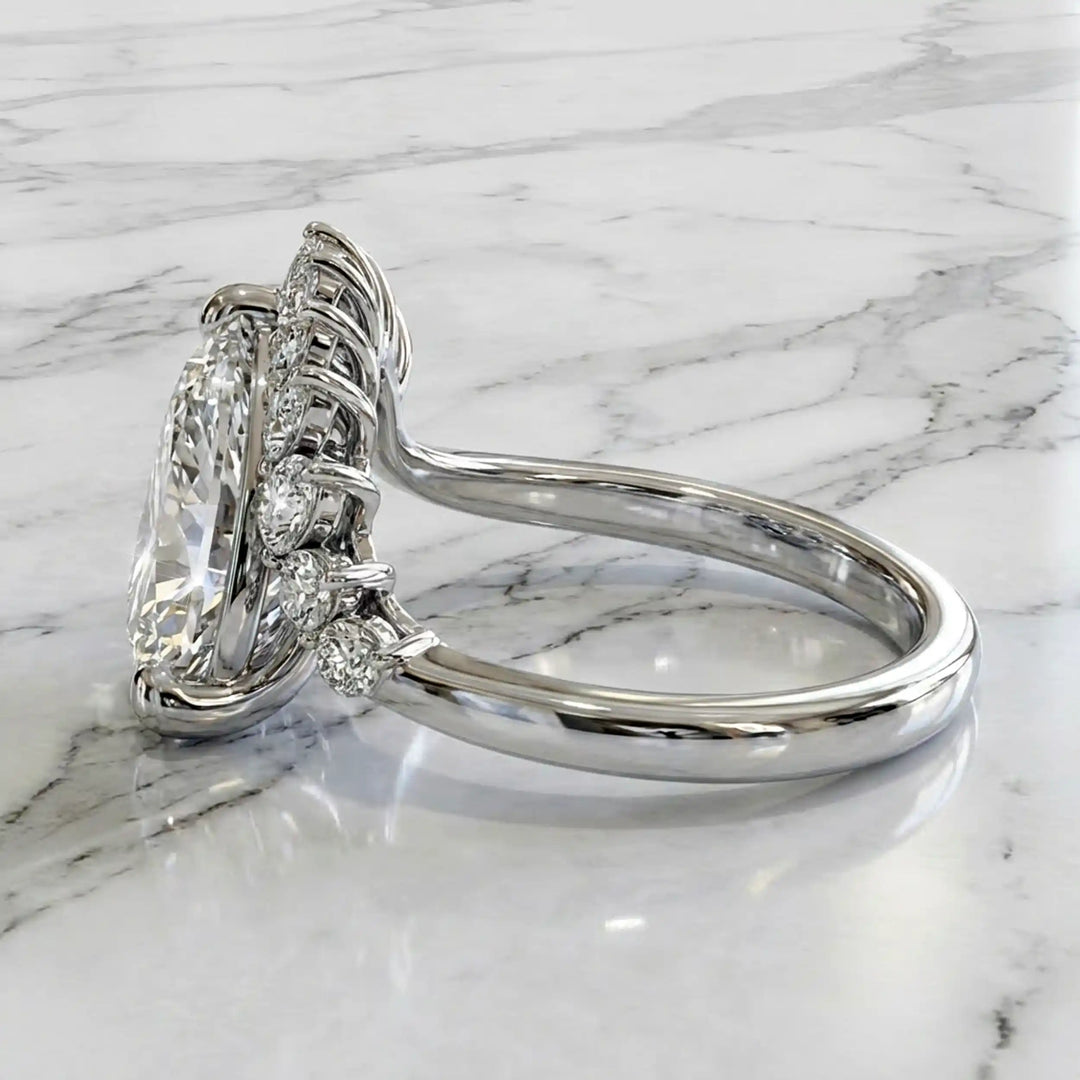 2.5 carat pear lab-grown diamond engagement ring with pear accents displayed on marble surface.
