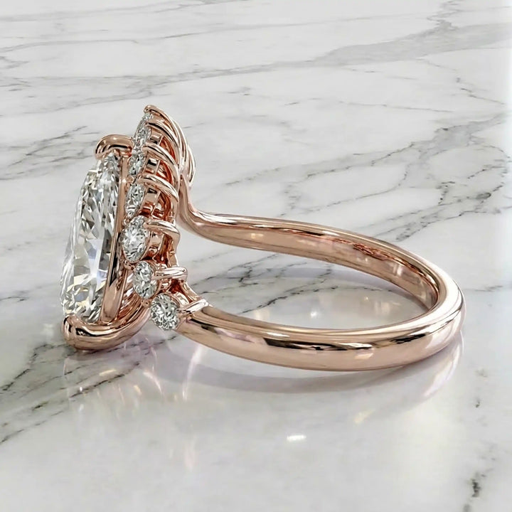 2.5 carat pear lab-grown diamond engagement ring with pear accents displayed on marble surface.
