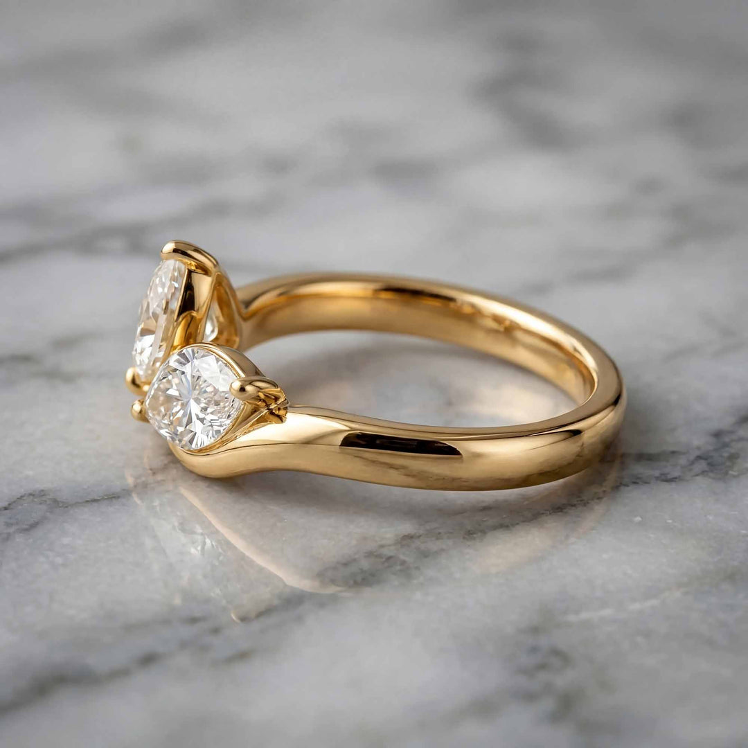 1.10 carat pear and marquise lab-grown diamond toi et moi engagement ring displayed on marble.
