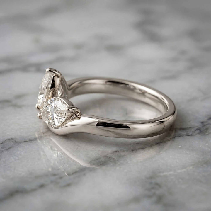 1.10 carat pear and marquise lab-grown diamond toi et moi engagement ring displayed on marble.
