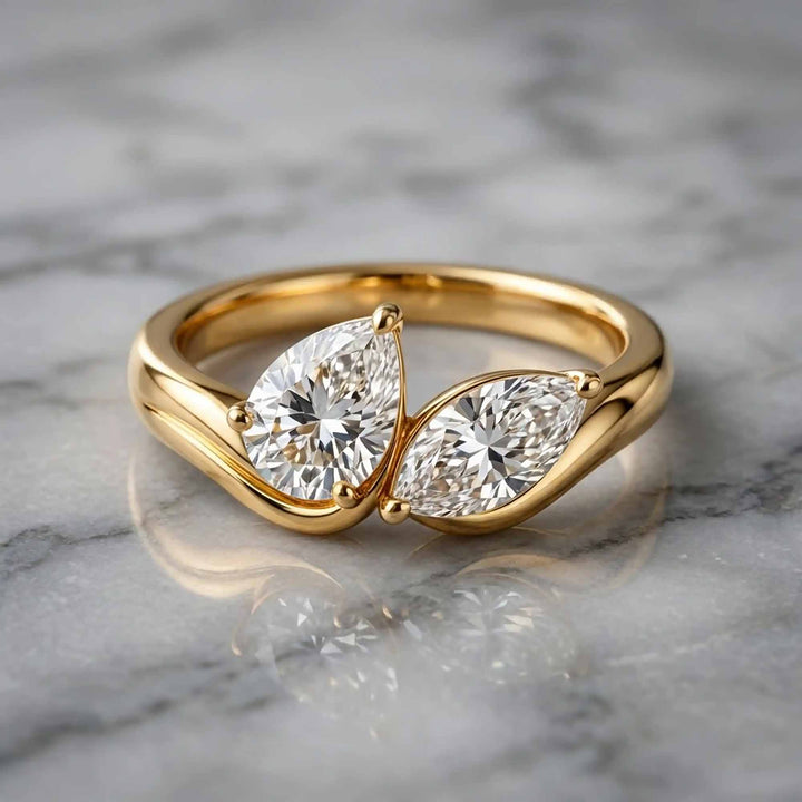 1.10 carat pear and marquise lab-grown diamond toi et moi engagement ring displayed on marble.

