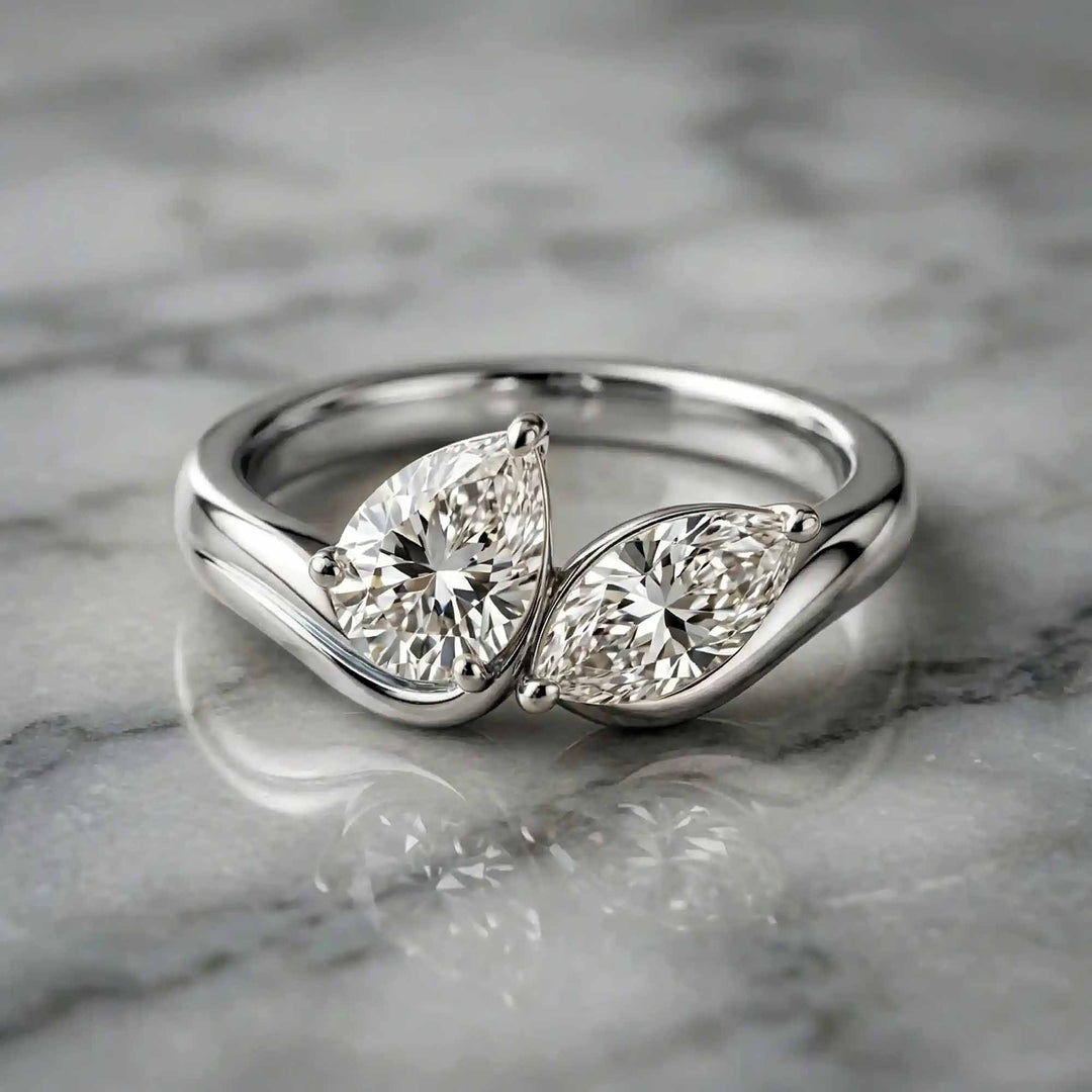 1.10 carat pear and marquise lab-grown diamond toi et moi engagement ring displayed on marble.
