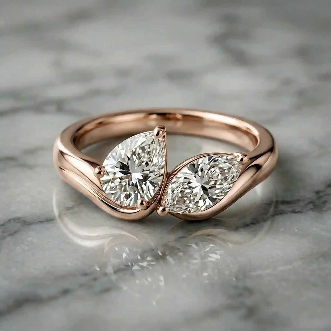1.10 carat pear and marquise lab-grown diamond toi et moi engagement ring displayed on marble.
