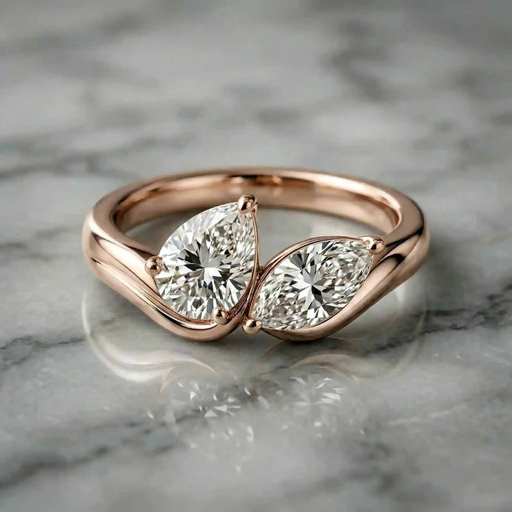 1.10 carat pear and marquise lab-grown diamond toi et moi engagement ring displayed on marble.

