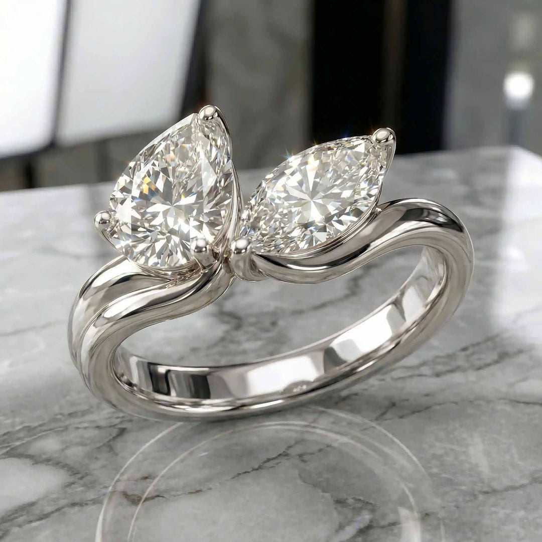 1.10 carat pear and marquise lab-grown diamond toi et moi engagement ring displayed on marble.
