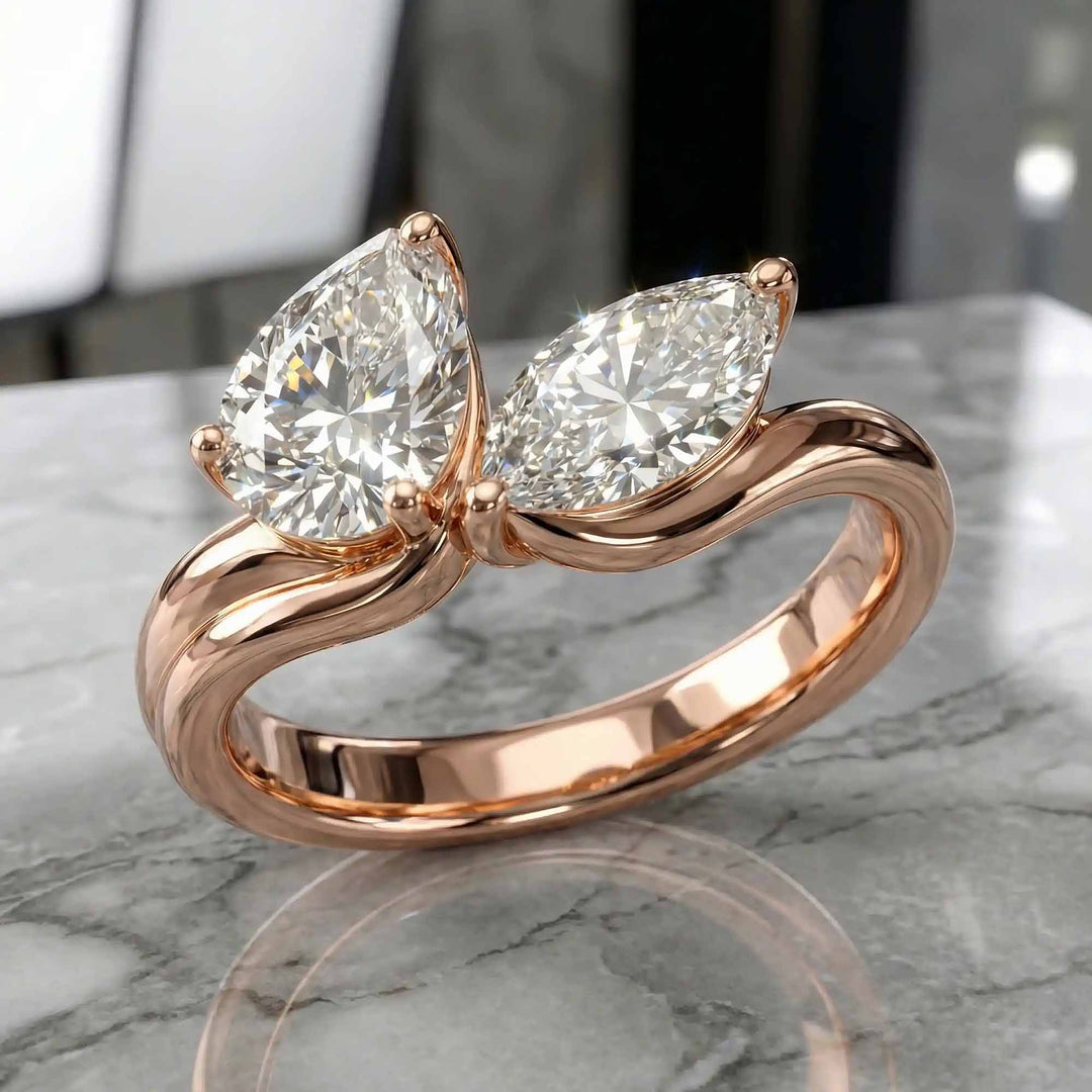 1.10 carat pear and marquise lab-grown diamond toi et moi engagement ring displayed on marble.
