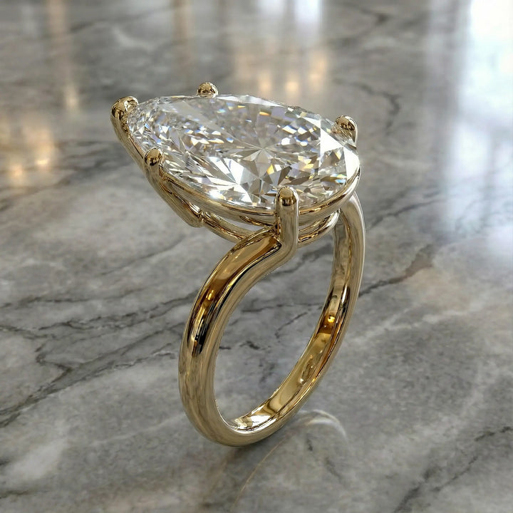 Pear-shaped lab-grown diamond cathedral solitaire engagement ring displayed on stone surface.
