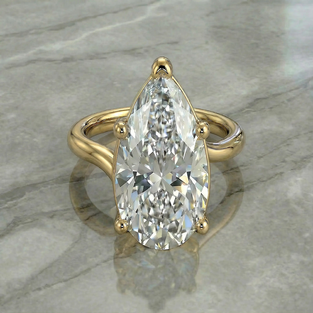Pear-shaped lab-grown diamond cathedral solitaire engagement ring displayed on stone surface.
