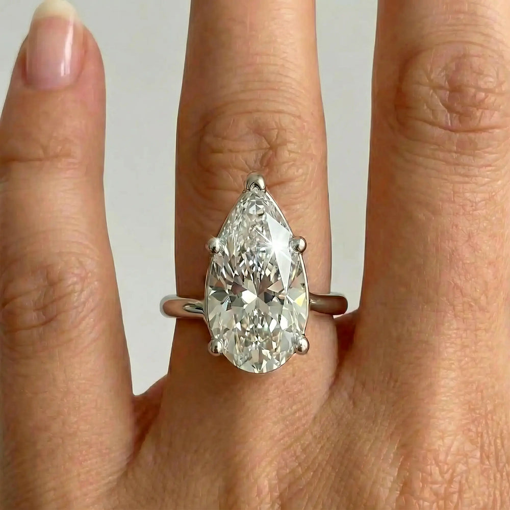 Pear-shaped lab-grown diamond cathedral solitaire engagement ring displayed on hand.
