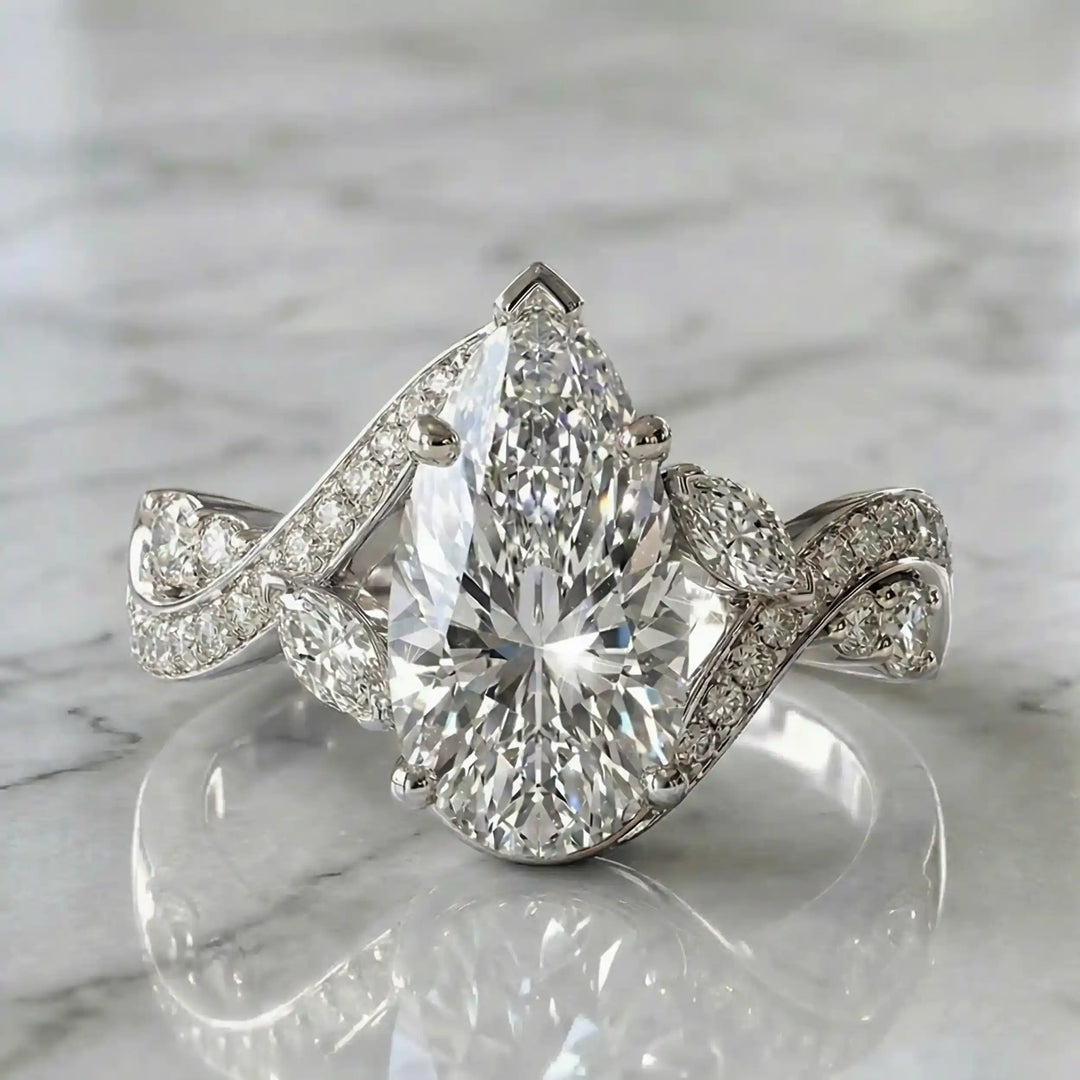 3 carat pear lab diamond twisted three-stone engagement ring displayed on marble surface.
