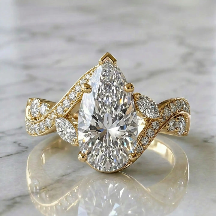 3 carat pear lab diamond twisted three-stone engagement ring displayed on marble surface.
