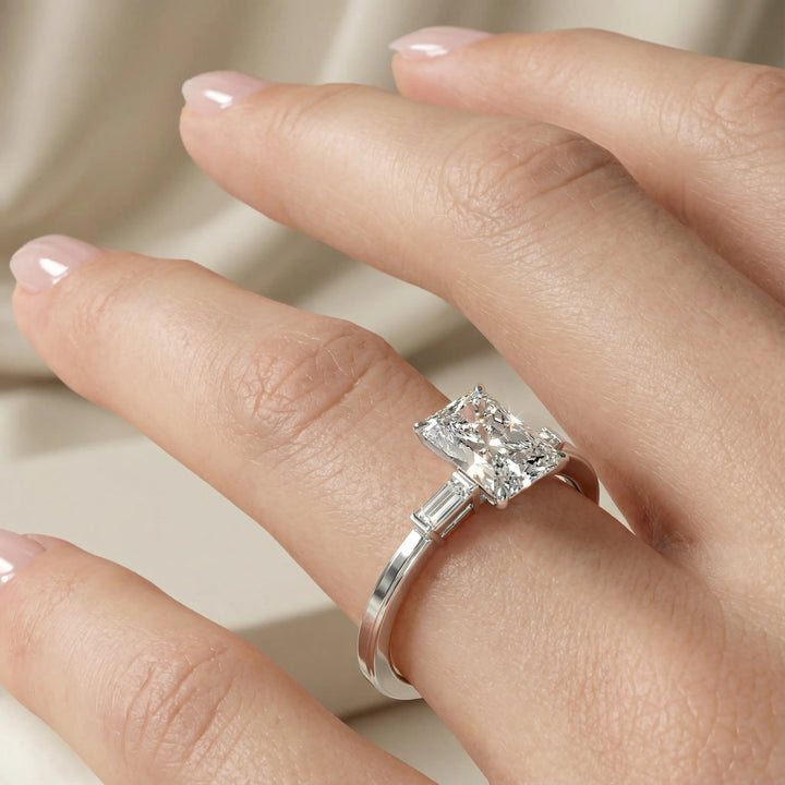 Radiant cut three stone engagement ring with tapered side diamonds.