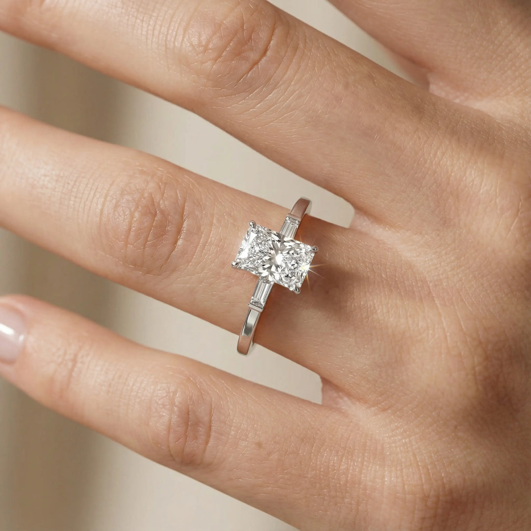 Radiant cut three stone engagement ring with tapered side diamonds.