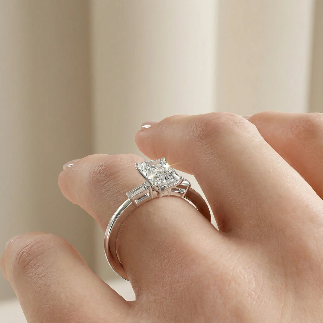 Radiant cut three stone engagement ring with tapered side diamonds.