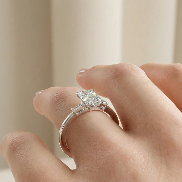 Radiant cut three stone engagement ring with tapered side diamonds.