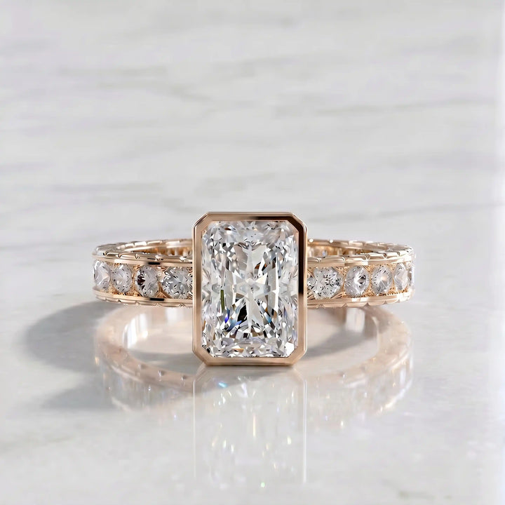 Radiant lab-grown diamond engagement ring with princess cut channel set band on marble display.