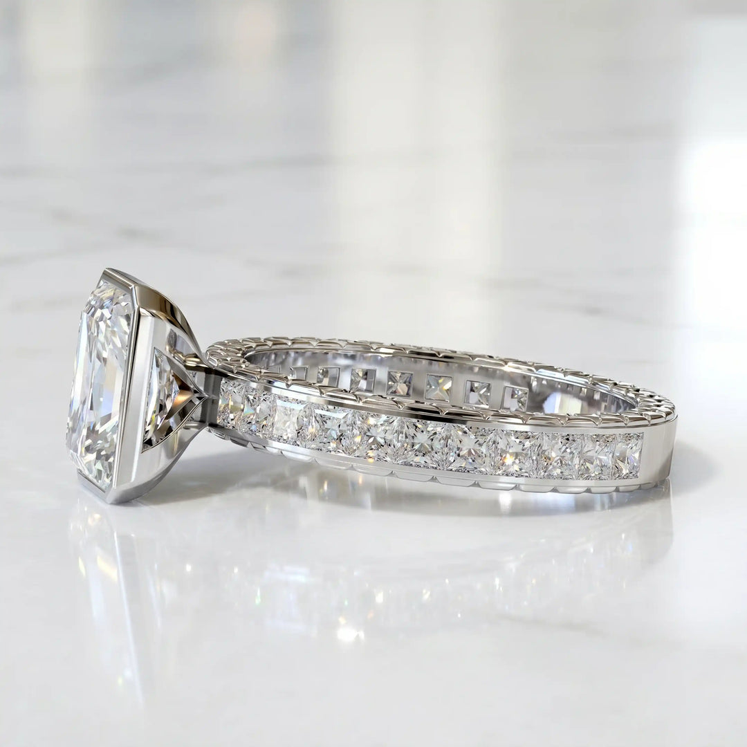 Radiant lab-grown diamond engagement ring with princess cut channel set band on marble display.