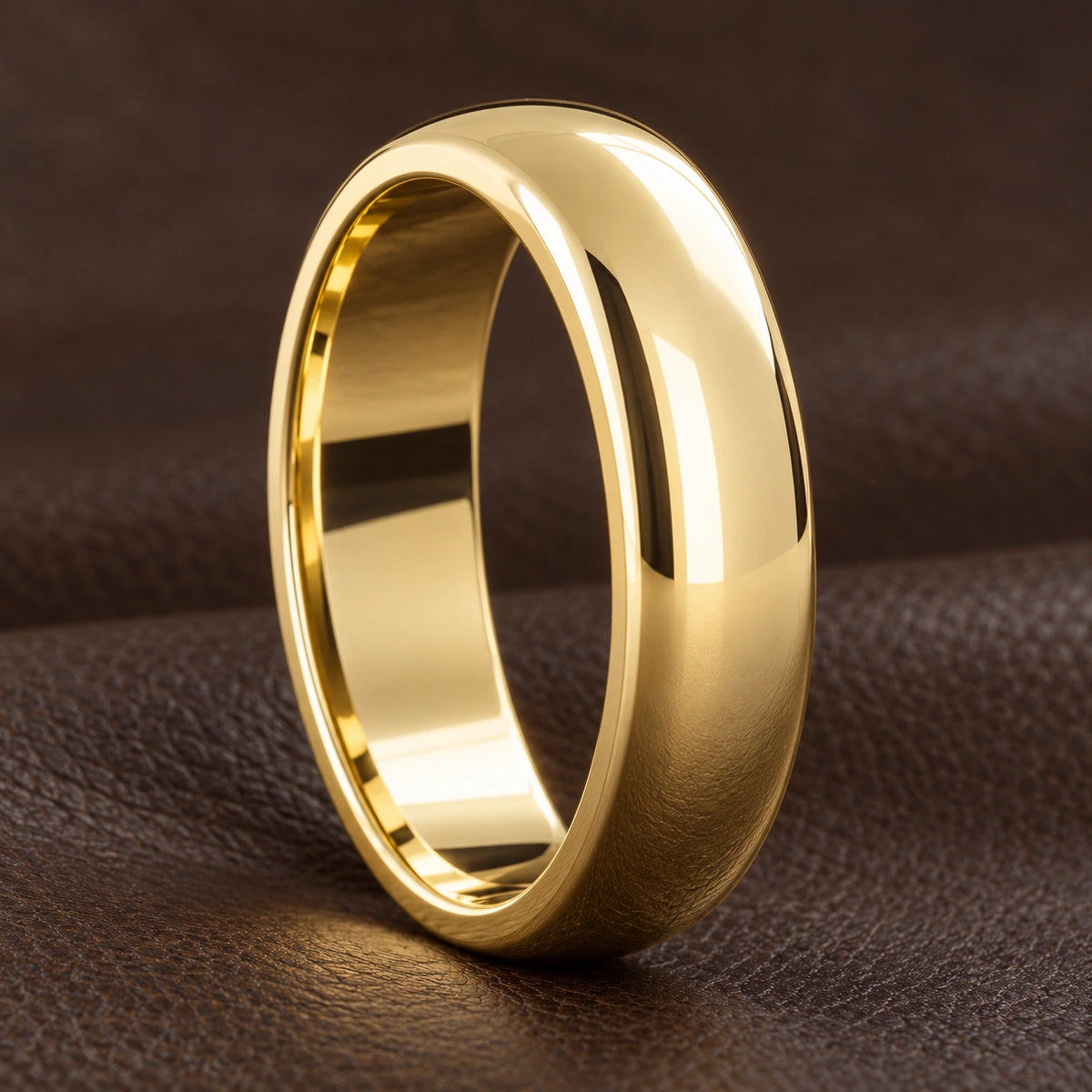 A polished yellow gold rounded wedding band on dark leather