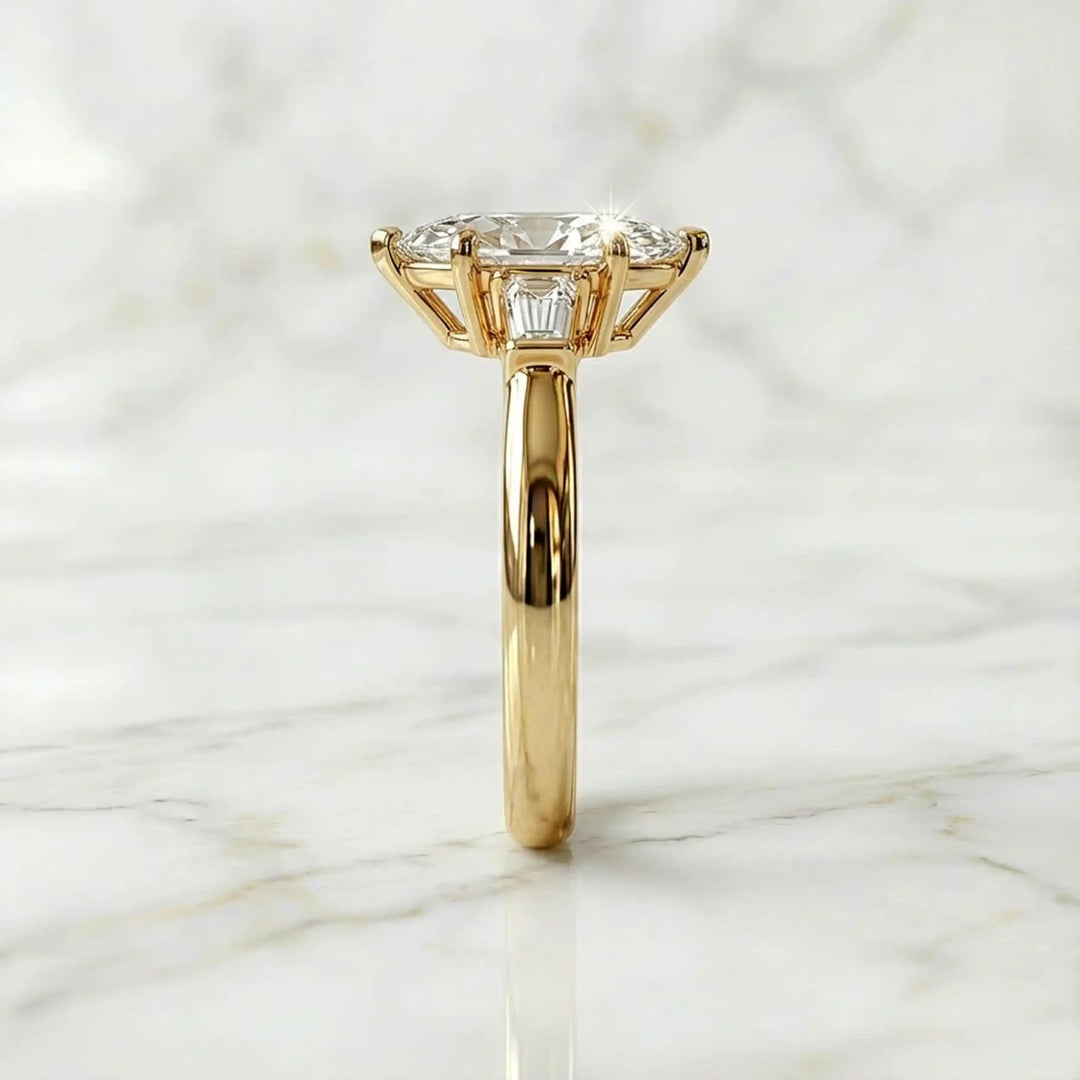 Three-stone marquise lab-grown diamond engagement ring displayed on marble surface.